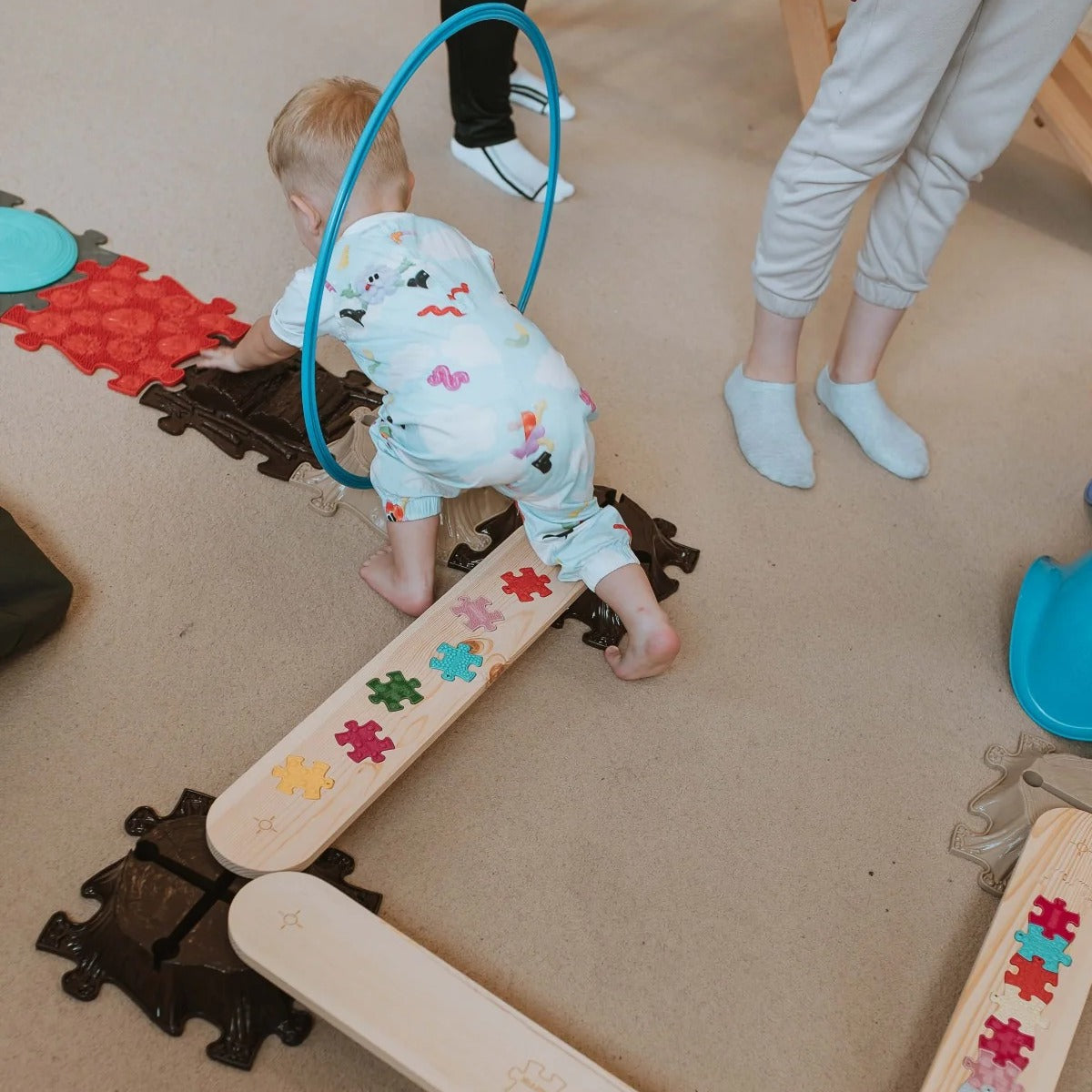 מבט מלמעלה על קורות איזון המחוברות למסלול פינה עם חלקי פאזל צבעוניים, וילד זוחל לאורכו